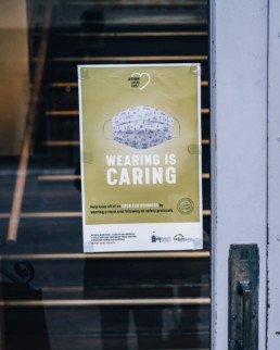 Poster in business window that reads 'Wearing is Caring'